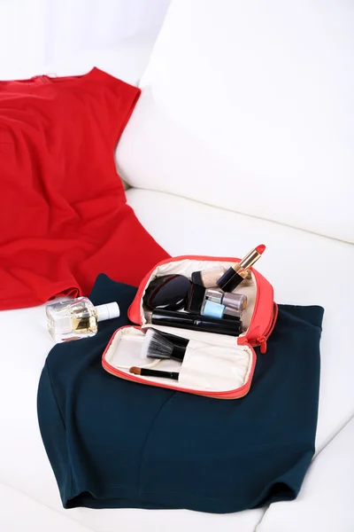Косметическая сумка, модная одежда, бутылка духов на диване на светлом фоне — стоковое фото