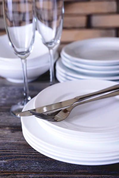 Set van witte gerechten op tafel op muur achtergrond — Stockfoto