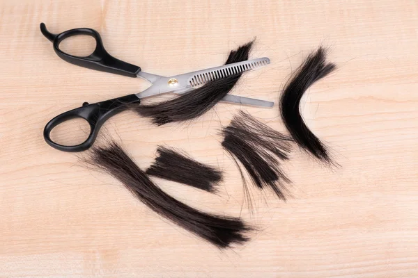 Вырезать волосы и ножницы на деревянном фоне — стоковое фото