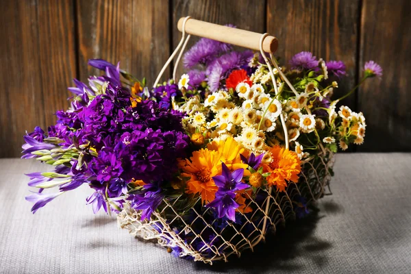 Hermosas flores silvestres en cesta sobre fondo de madera — Foto de Stock