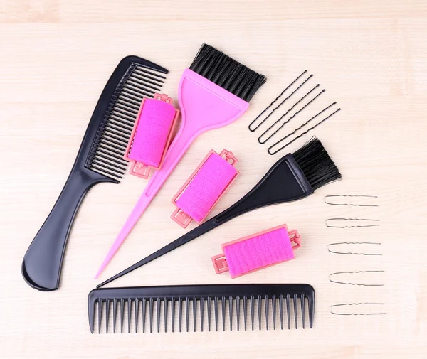 Professional hairdresser tools - comb, scissors, pins and curlers on light wooden background — Stock Photo, Image