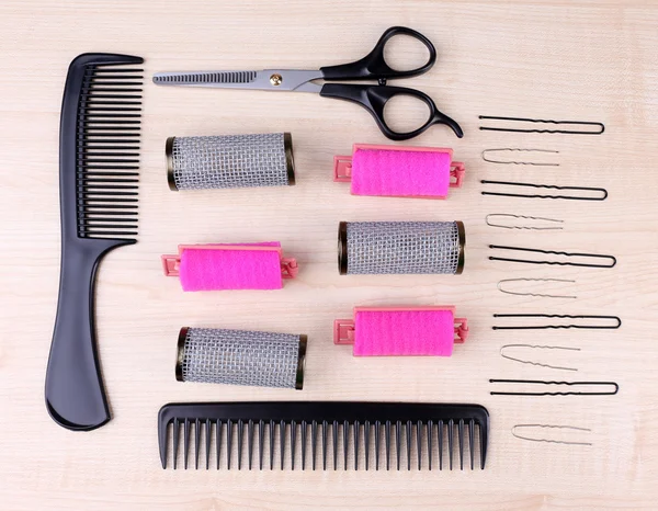 Outils professionnels pour coiffeur peigne, ciseaux et broches sur fond bois clair — Photo