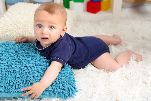 Cute baby boy lying on floor in room — Stock Photo, Image