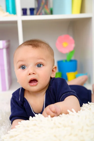 Cute baby boy lying on floor in room — Stock Photo, Image