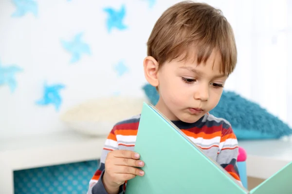 Симпатичный маленький мальчик читает книгу в комнате — стоковое фото