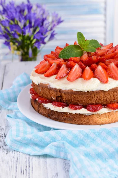Delicious biscuit cake with strawberries on table on light background — Stock Photo, Image