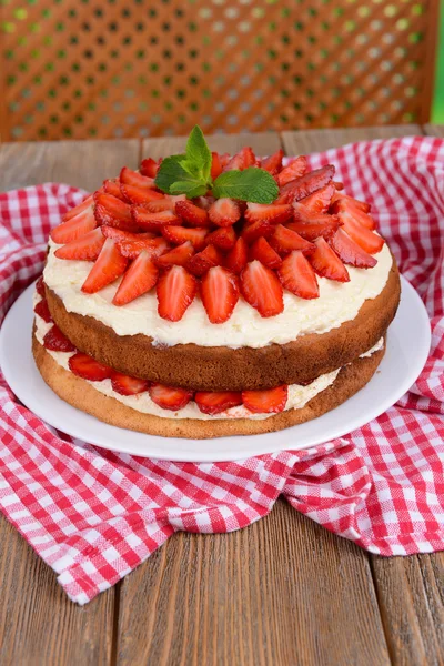 Delicious biscuit cake with strawberries on table on brown background — Stock Photo, Image