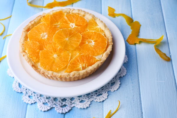 Crostata all'arancia fatta in casa su piatto, su sfondo di legno a colori — Foto Stock