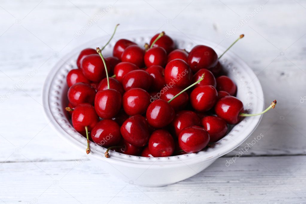 Sweet cherries in bowl on wooden background