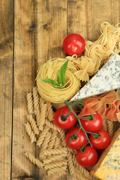 Verschiedene Nudeln, Käse und Tomaten auf Holztisch in Großaufnahme — Stockfoto