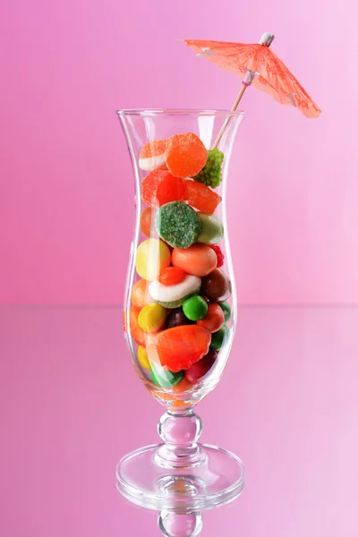 Diferentes dulces de frutas de colores en vidrio sobre fondo rosa — Foto de Stock