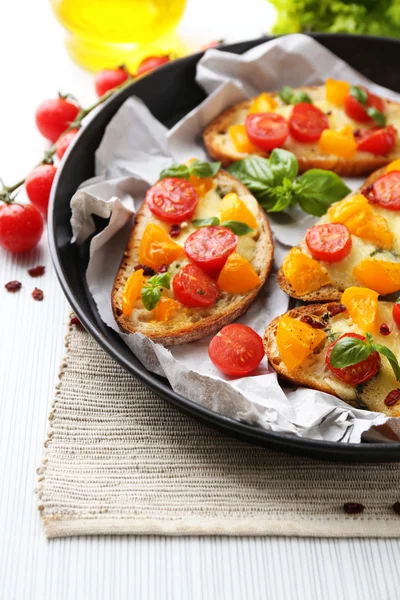 Smakelijke bruschetta met tomaten in pan, op tafel — Stockfoto