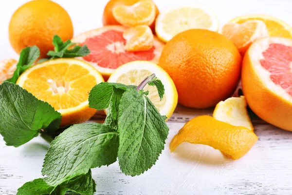 Färska citrusfrukter med gröna blad på färg trä bakgrund — Stockfoto