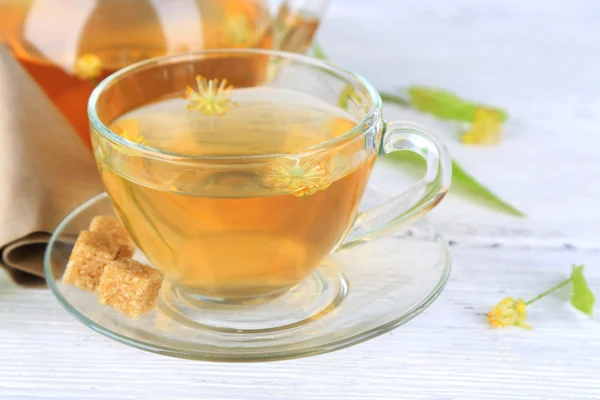 Chá de ervas saboroso com flores de tília na mesa de madeira — Fotografia de Stock