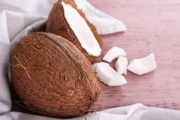 Coco quebrado com guardanapo em fundo de madeira — Fotografia de Stock