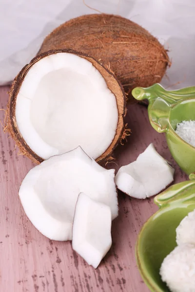 Noix de coco cassée avec des bonbons sur fond en bois — Photo