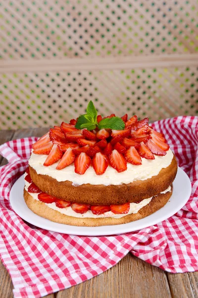 Heerlijke biscuit cake met aardbeien op tafel op beige achtergrond — Stockfoto