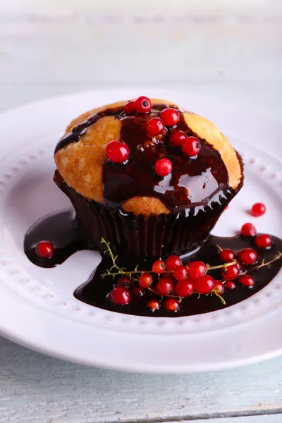 Ahşap zemin üzerinde plaka üzerinde çikolata soslu lezzetli muffin — Stok fotoğraf