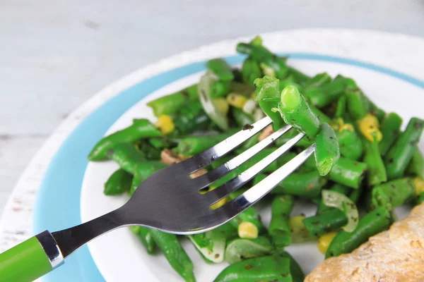 Salat mit grünen Bohnen, Schinken und Mais auf Teller, auf farbigem Holzgrund — Stockfoto