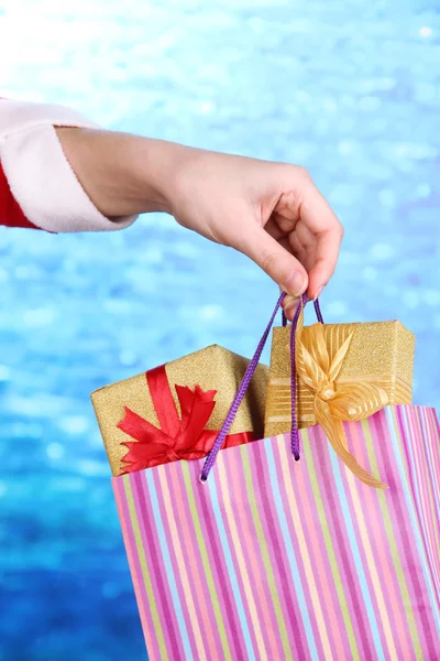 Hand holds package with New Year gifts on blue background — Stock Photo, Image