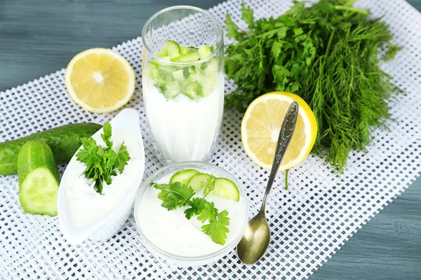 Gurka yoghurt i glas och skål, på färg servett — Stockfoto