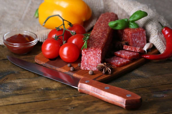 Leckere Salamiwurst und Gewürze auf Holzgrund — Stockfoto