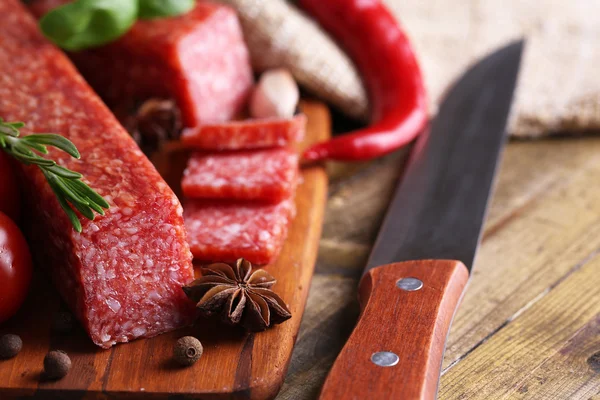 Sabrosa salchicha salami y especias sobre fondo de madera —  Fotos de Stock