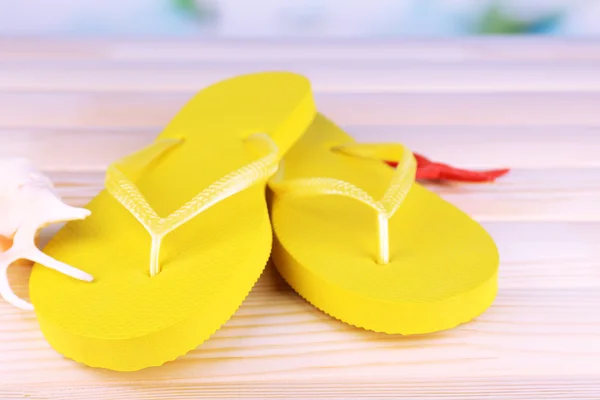 Bright flip-flops on wooden table, on nature background — Stock Photo, Image