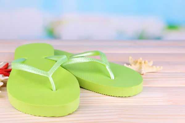 Bright flip-flops on wooden table, on nature background — Stock Photo, Image