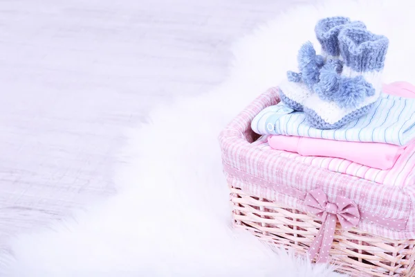 Baby clothes in basket on floor in room — Stock Photo, Image