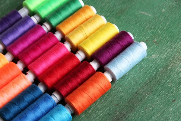 Multicolor sewing threads on wooden background — Stock Photo, Image