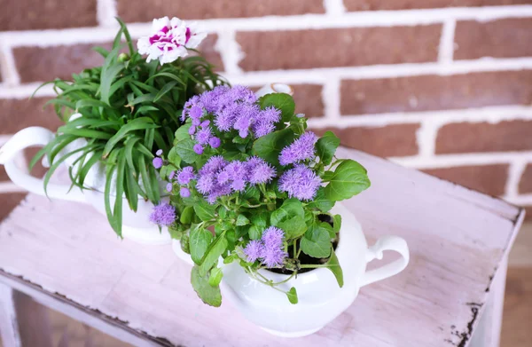 Bloemen in decoratieve potten op houten ladder, op bakstenen achtergrond — Stockfoto