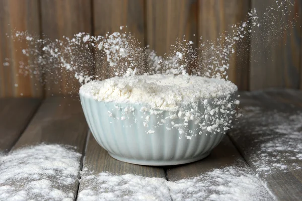 Farinha na tigela na mesa sobre fundo de madeira — Fotografia de Stock