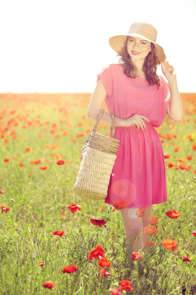 美しい若い女性にケシ畑で枝編み細工品の袋を保持 — ストック写真