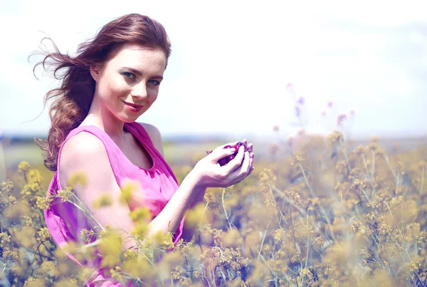 Mooie jonge vrouw met kersen in veld — Stockfoto