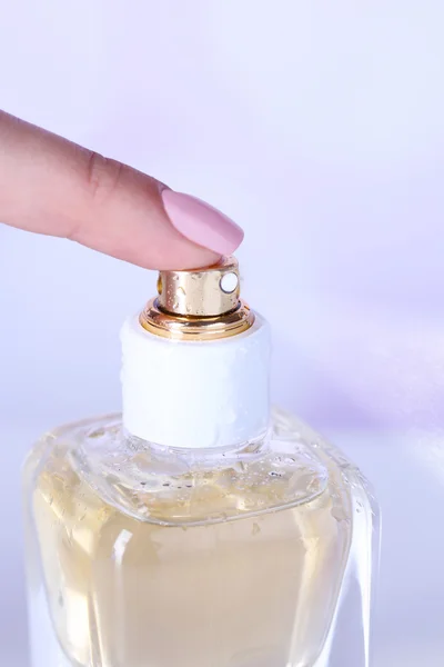 Bottle of perfume in hand on bright background