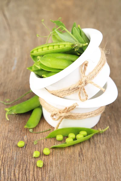 Frische grüne Erbsen in Schüssel auf Holztisch — Stockfoto