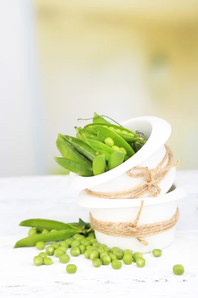 Färska gröna ärtor i skål på träbord — Stockfoto