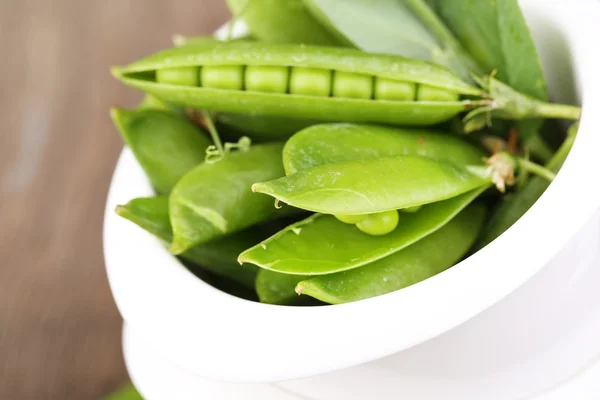 木のテーブルの上のボウルに新鮮な緑のエンドウ豆 — ストック写真