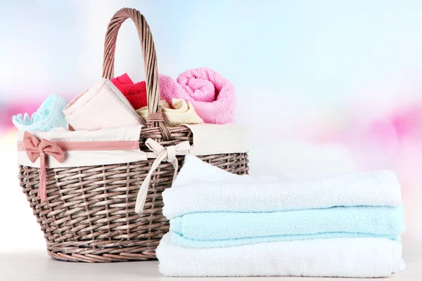 Colorful towels in basket, on table, on bright background — Stock Photo, Image