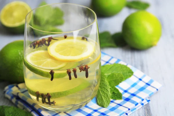 Bevanda estiva fresca con lime e chiodi di garofano in vetro, su sfondo di legno a colori — Foto Stock