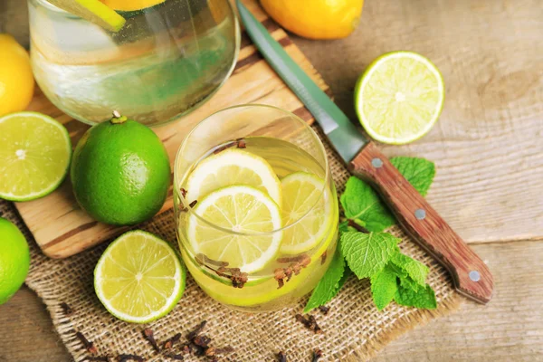 Fresh summer drink with lime and cloves in glass, on color wooden background — Stock Photo, Image