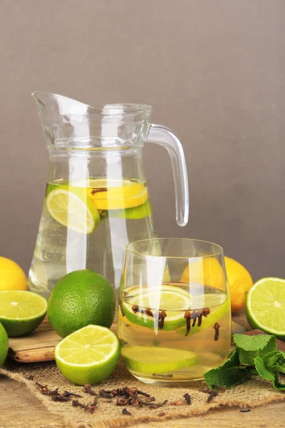 Čerstvé letní drink s limetkou a Hřebíček do skla a džbán, na dřevěné tabulce barev, na světlé pozadí — Stock fotografie