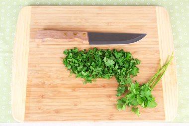 tablo üzerinde kesme tahtası üzerinde bıçakla doğranmış yeşillikleri