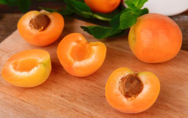 Olgun kayısı ile yeşil nane yaprakları ahşap zemin üzerinde kesme tahtası üzerinde