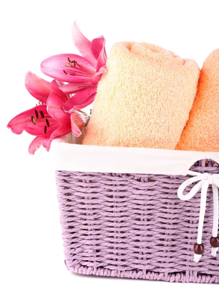 Color towels and lily flowers in wicket basket, isolated on white — Stock Photo, Image