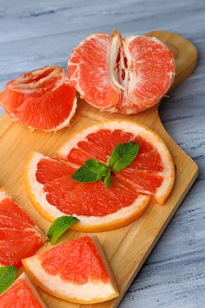 Zralých grapefruitů na prkénko, na dřevěný stůl, na světlé pozadí — Stock fotografie