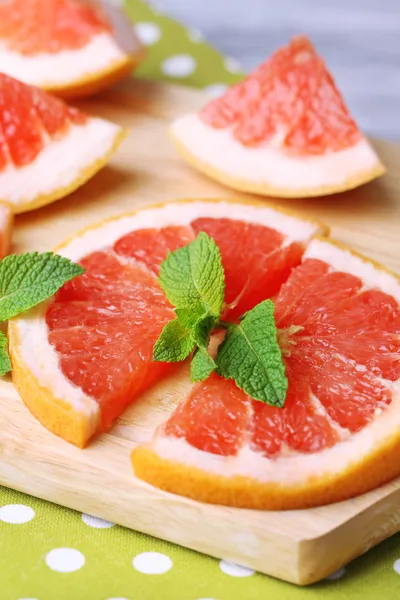 Ripe grapefruits on cutting board, on wooden table, on light background — Stock Photo, Image