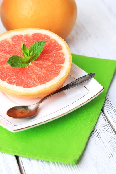 Половина грейпфрута и ложка на тарелке на светлом фоне — стоковое фото