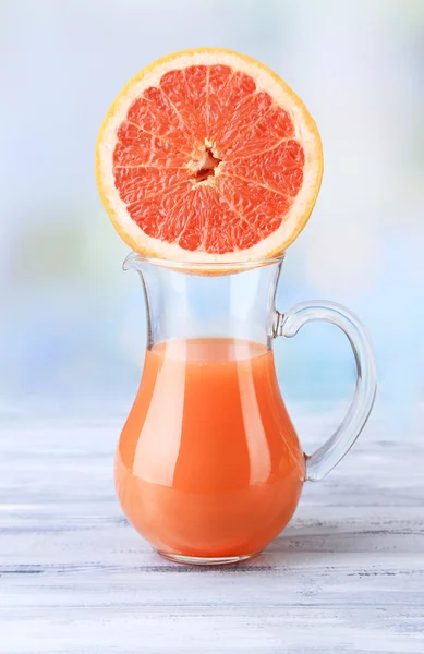 Grapefruitsap in glas kruik op een houten achtergrond kleur — Stockfoto